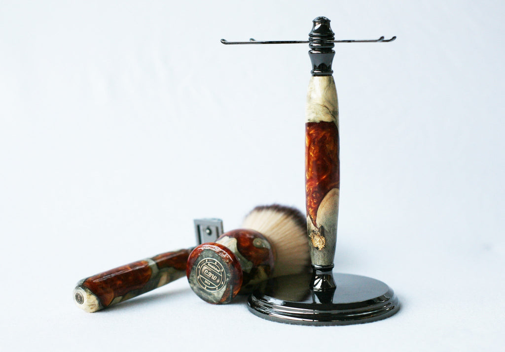 Rasierset aus Buckeye-Maserholz mit Sicherheitsrasierer aus Harz in Gold-Rot-Maserung, 26-mm-Rasierpinsel und passendem Rasierständer.